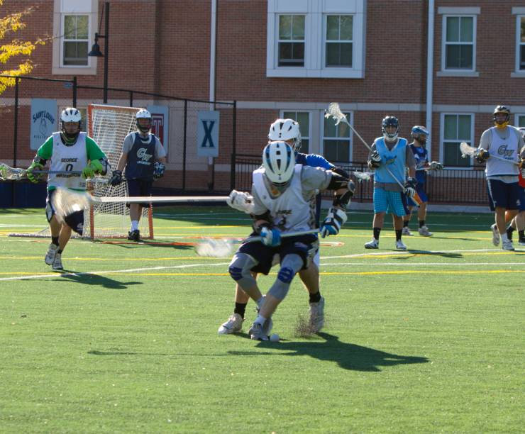 Men's lacrosse players run across the field