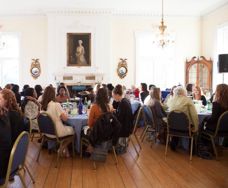 Post Hall set with round tables and filled with women eating lunch.