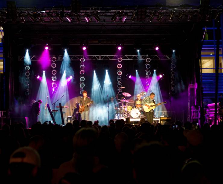 Musicians play on a lit stage at night.