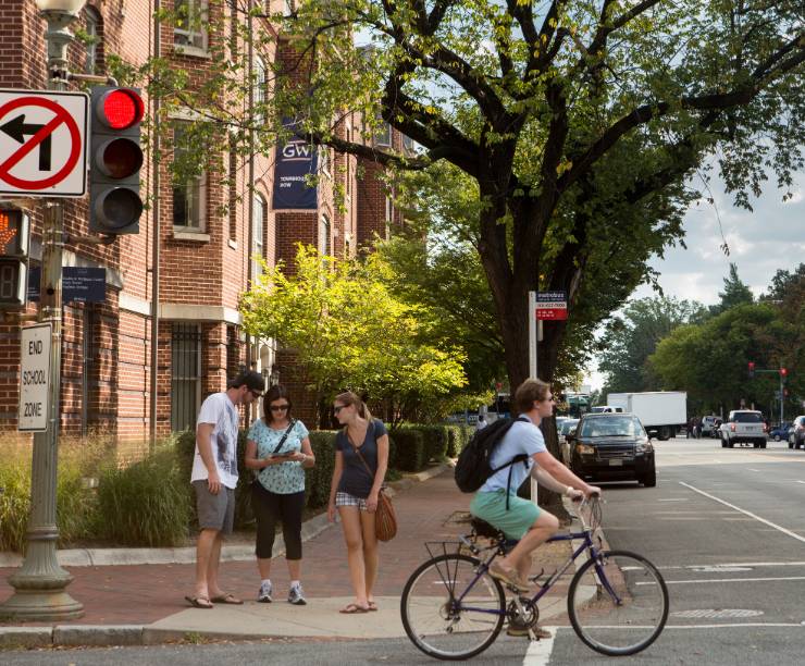 Pedestrians and a bicyclist pass Townhouse Row.