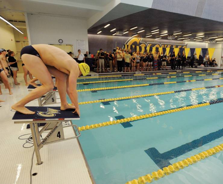 Swimmers prepare to dive into the pool at the start of a race.