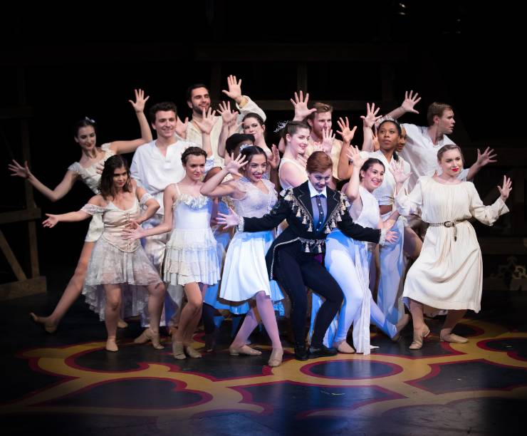 A group of students in costumes sing a musical number onstage.