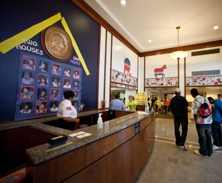 Students walk into a common area past a front desk.