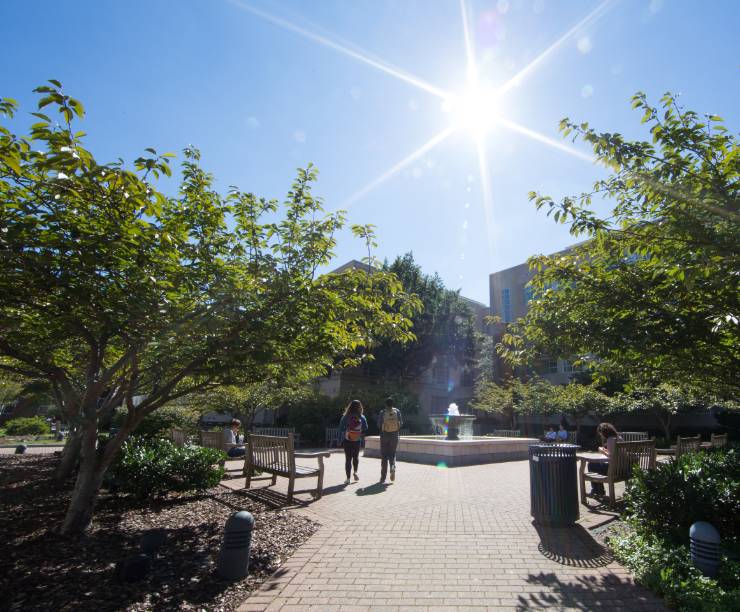 Students walk by the fountain, surrounded by courtyard and trees.