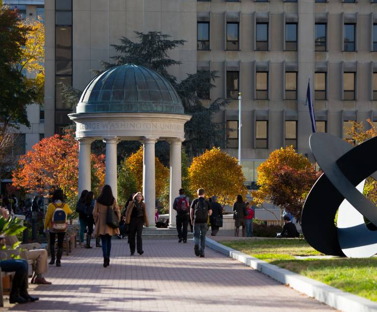 Student walk through Mid-Campus Quad by the Tempietto and large sculpture.