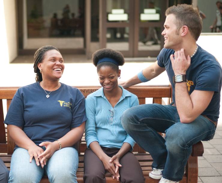 A man and women laugh together on a bench.