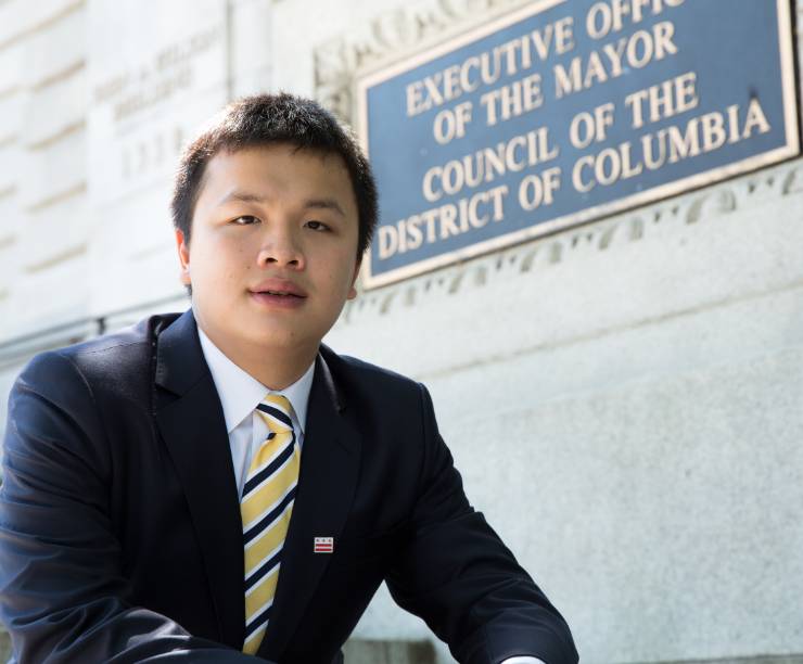 A student in a suit sits on the steps in front of the deputy mayor's office.