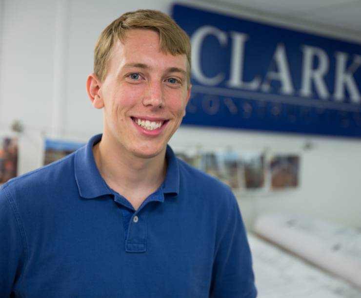 A student stands in front of a Clark Construction sign.