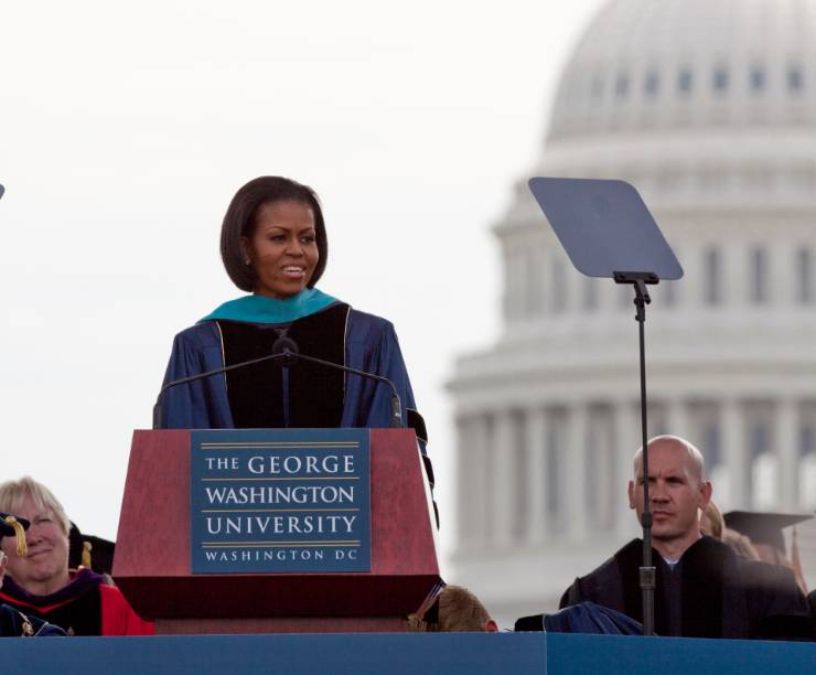 Michelle Obama speaks at the GW Commencement with the Capitol building behind her.