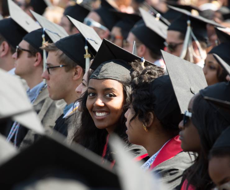 Students in academic regalia smile for the camera.