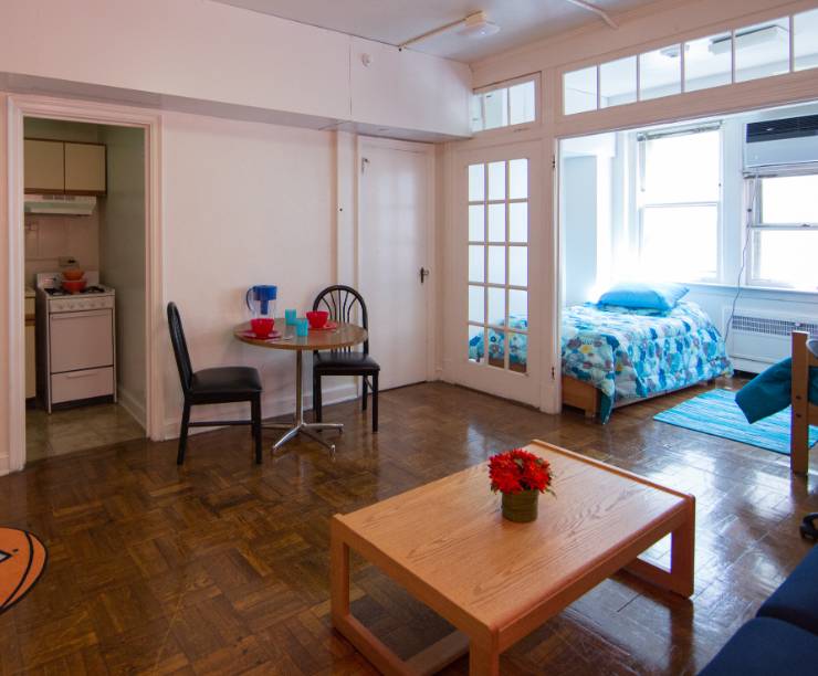 A living room with a view of a double-bedroom and the doorway to the kitchen.