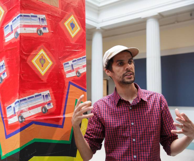 Student standing next to a piece of artwork.