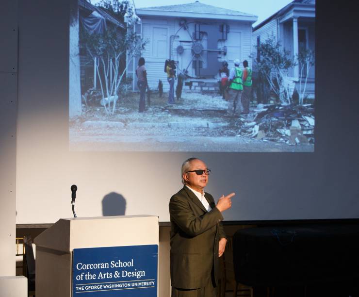 Professor Mel Chin speaking in front of a projector slide.