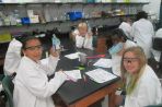 Kids in lab coats and safety goggles around a table in the lab at the BTCI.