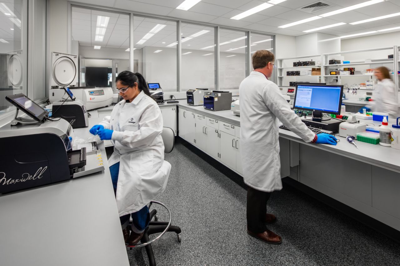 Three scientists in lab coats work at their desks in Feynman labs.