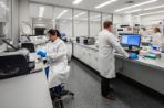 Three scientists in lab coats work at their desks in Feynman labs.