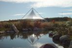 A picture of the white peaked Agora Pavilion from the small pond nearby.