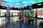 The Feynman workout room during a class with people on mats and a disco ball throwing colors across the room.