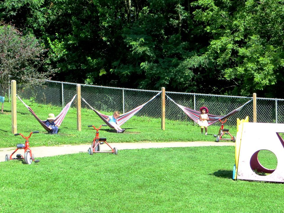 Children at Woods Hollow sit in their hammocks outside.