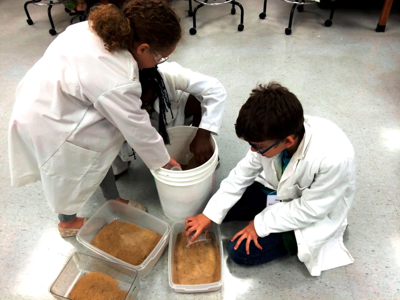 Two kids experimenting with buckets of sand.