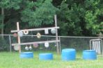 Pots and pans hang from wooden beams with blue barrels of different sizes to mark where children can have outdoor music time.