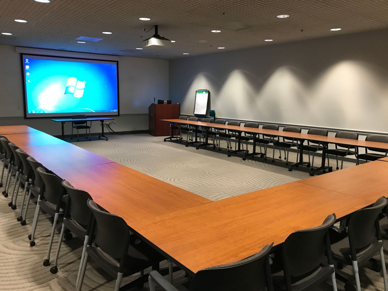 A meeting room on the first floor of the BTC with a large projector in the front, a podium and tables and chairs forming a 