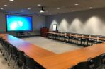 A meeting room on the first floor of the BTC with a large projector in the front, a podium and tables and chairs forming a 