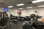 The workout room of the BTC which includes floor to ceiling mirrors, treadmills, free weights, machines and a mounted television.