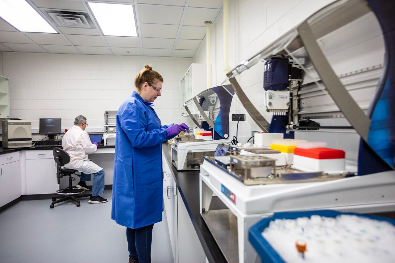 Two scientists in lab coats working in a lab with machines in the RFC.