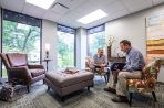 Two people are meeting in one of the RFC third spaces, a room with mulitple comfy chairs.