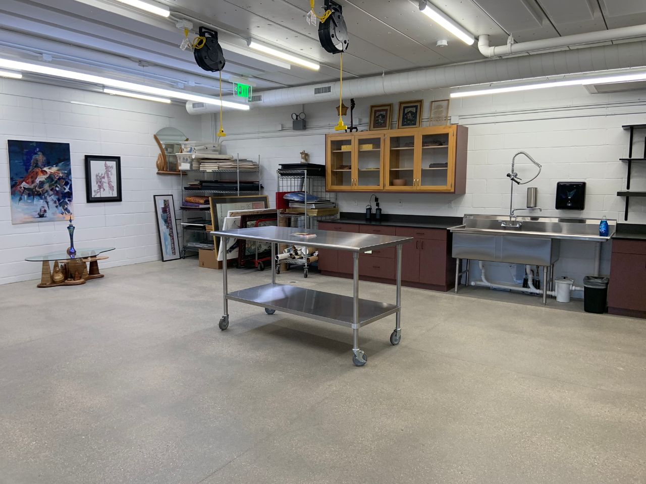 The Louvre West workspace includes two sinks against the walls, a rolling table, extension cables hanging from the ceiling, and artwork.