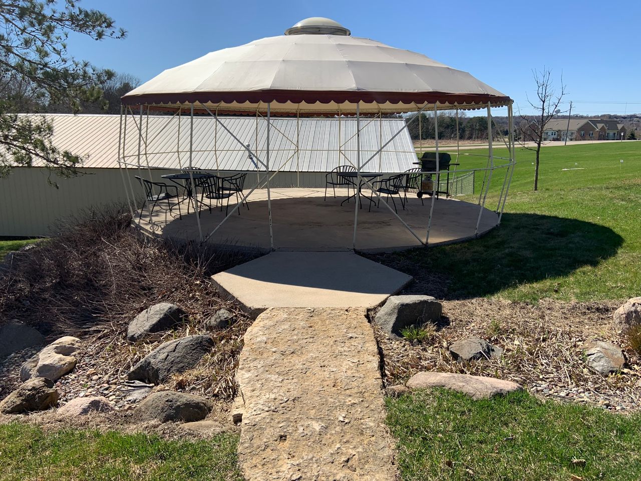 A circular patio that contains chairs and a grill.