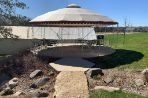 A circular patio that contains chairs and a grill.