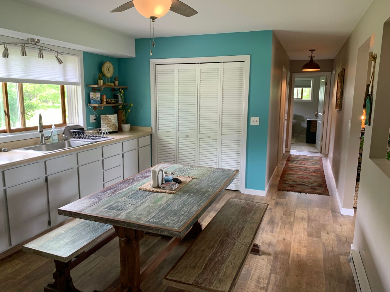 hard wood floor kitchen with a picnic table, white cupboards, blue walls