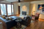 this is a hard wood floor room with a fireplace on the right wall and a leather couch and chair facing the fireplace with a leather ottoman. On the far wall are floor to ceiling glass sliding doors.