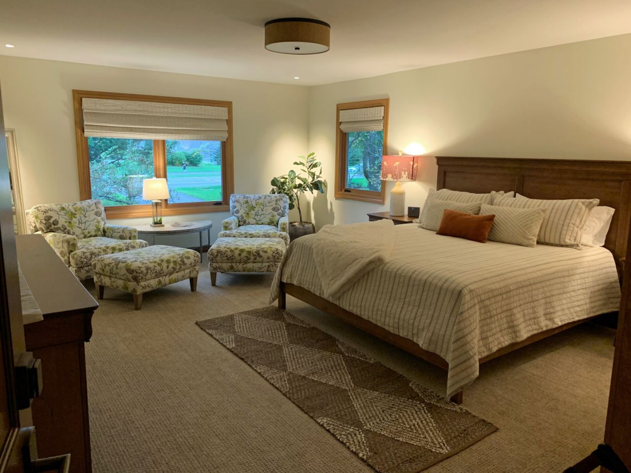 a king bed against the right wall with two lounge chairs against the far wall and a dresser on the left wall