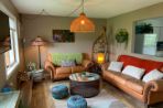 two leather couches with a circular table and geometric rug with hanging ceiling lamp