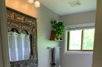 bathroom with small vanity and mirror, wood floors and toilet in the corner