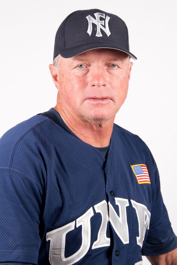 A head and shoulders shot of a Caucasian male in a blue, gray and white baseball uniform and hat.