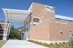 Three-story brick building with white trim connected to an adjoining building with a tall white awning over a wide walkway; The back of the building features a tile mosaic of an osprey swooping into a nest.