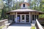 One story off-white hexagonal building with wood paneling and windows on all sides sits on a wide wooden walkway that leads into UNF’s wooded natural preserve.