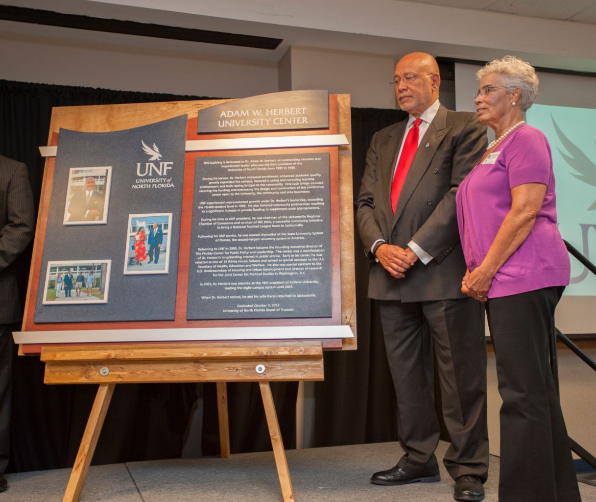 Adam W. and Karen Herbert stand with a dedication plaque for the Adam W. Herbert University Center.