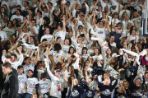 A large group of people cheering at a basketball game.