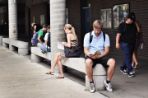 Students sitting on concrete benches reading and a few students walk by.