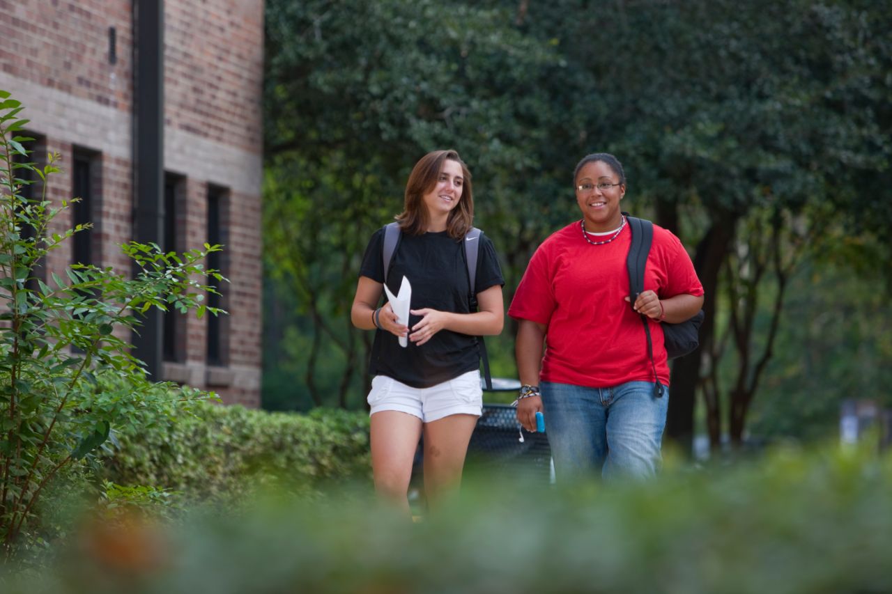 Two females walking on a sidewalk.