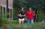 Two females walking on a sidewalk.