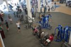 A view of the fitness center from the thrid floor. People working out a various machines.