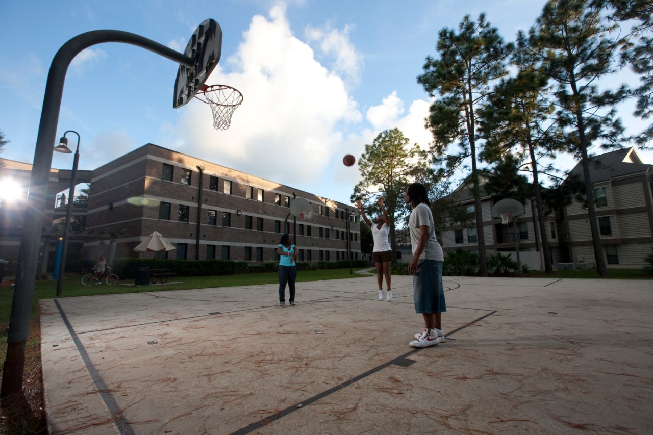 Two females and one male play basketball on the court.