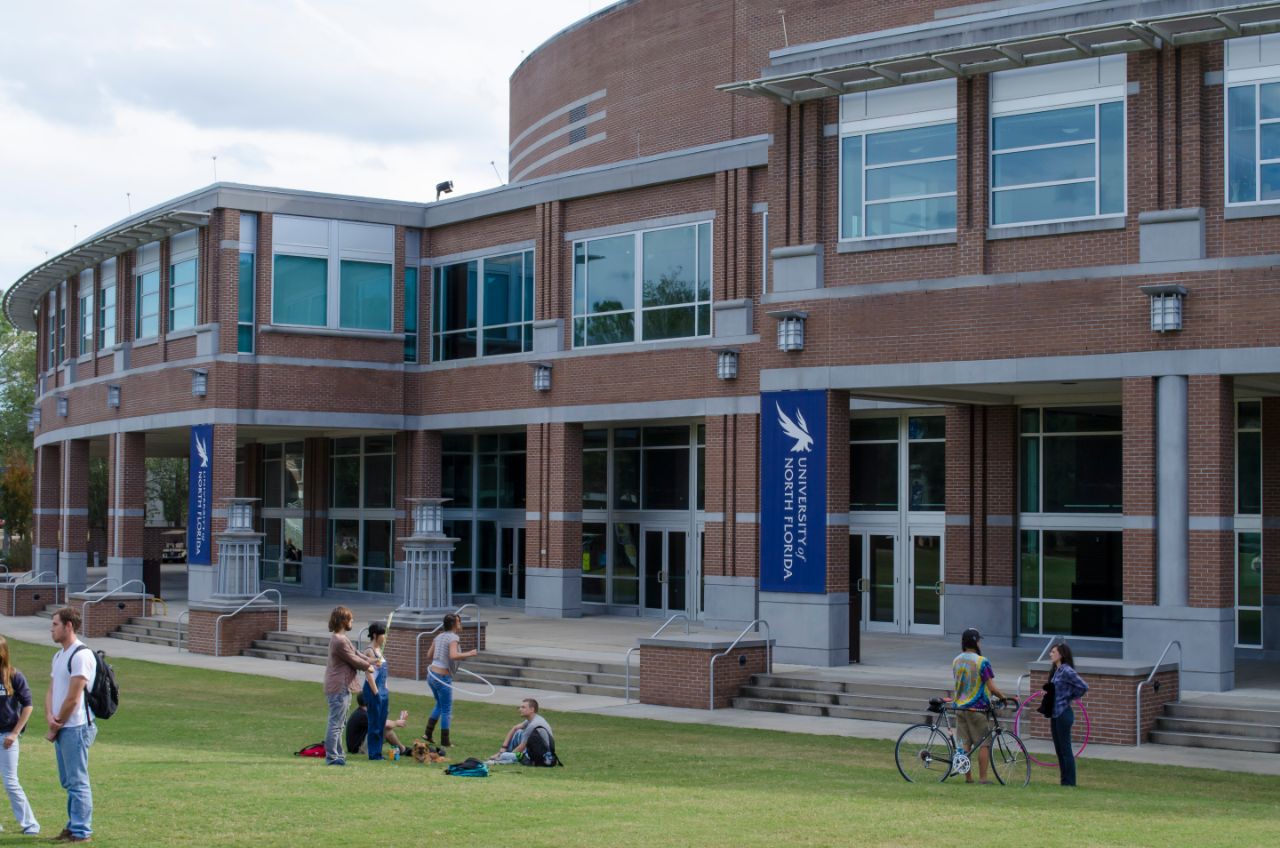 Two groups of students in front of the Fine Arts Center. The first group is hulu hooping and the other two students are talking.