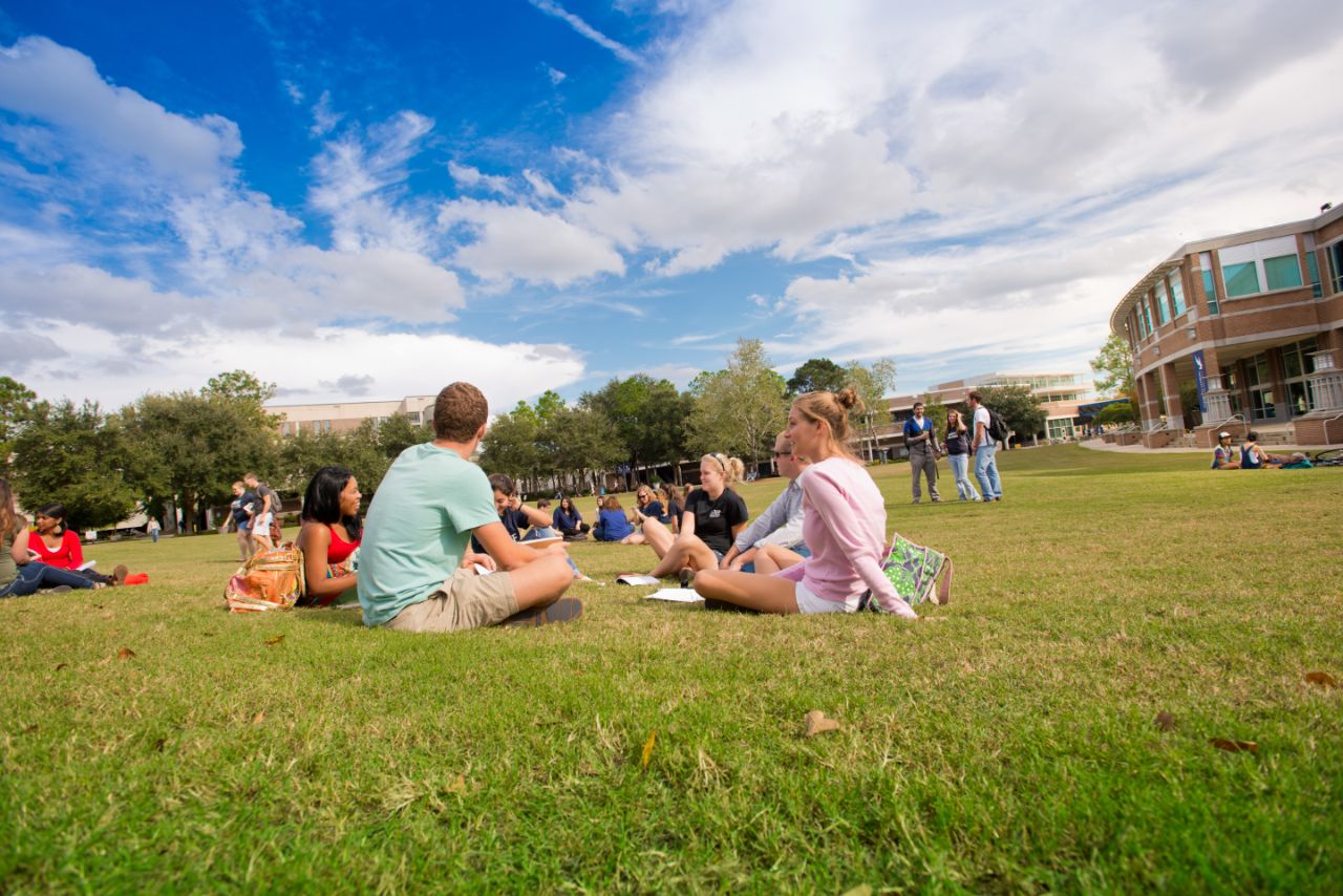 Several groups of students sitting and standing around the Green.